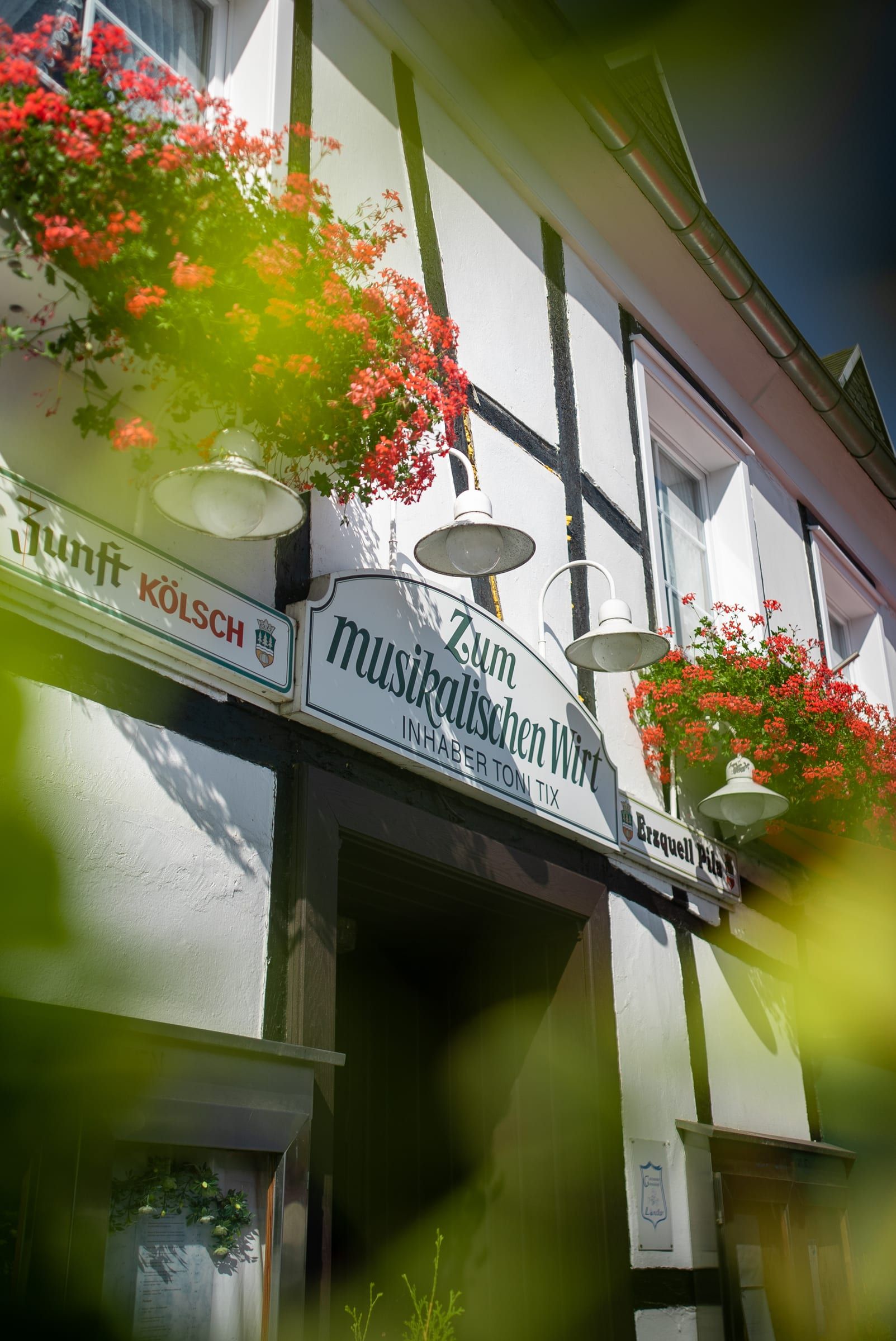 Historisches Wirtshausschild mit der Aufschrift „Zum musikalischen Wirt, Inhaber Toni Tix“